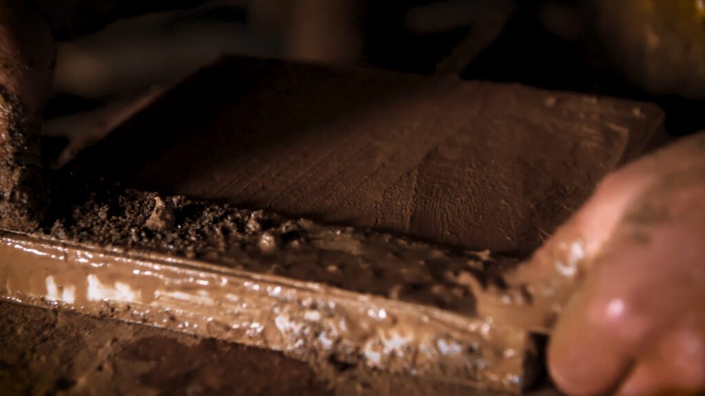 Das Erbe alter Meister – So entstehen unsere handgefertigten Terracotta Fliesen Detailaufnahme einer frisch geformten Terracotta-Fliese – noch feucht, roh und lebendig