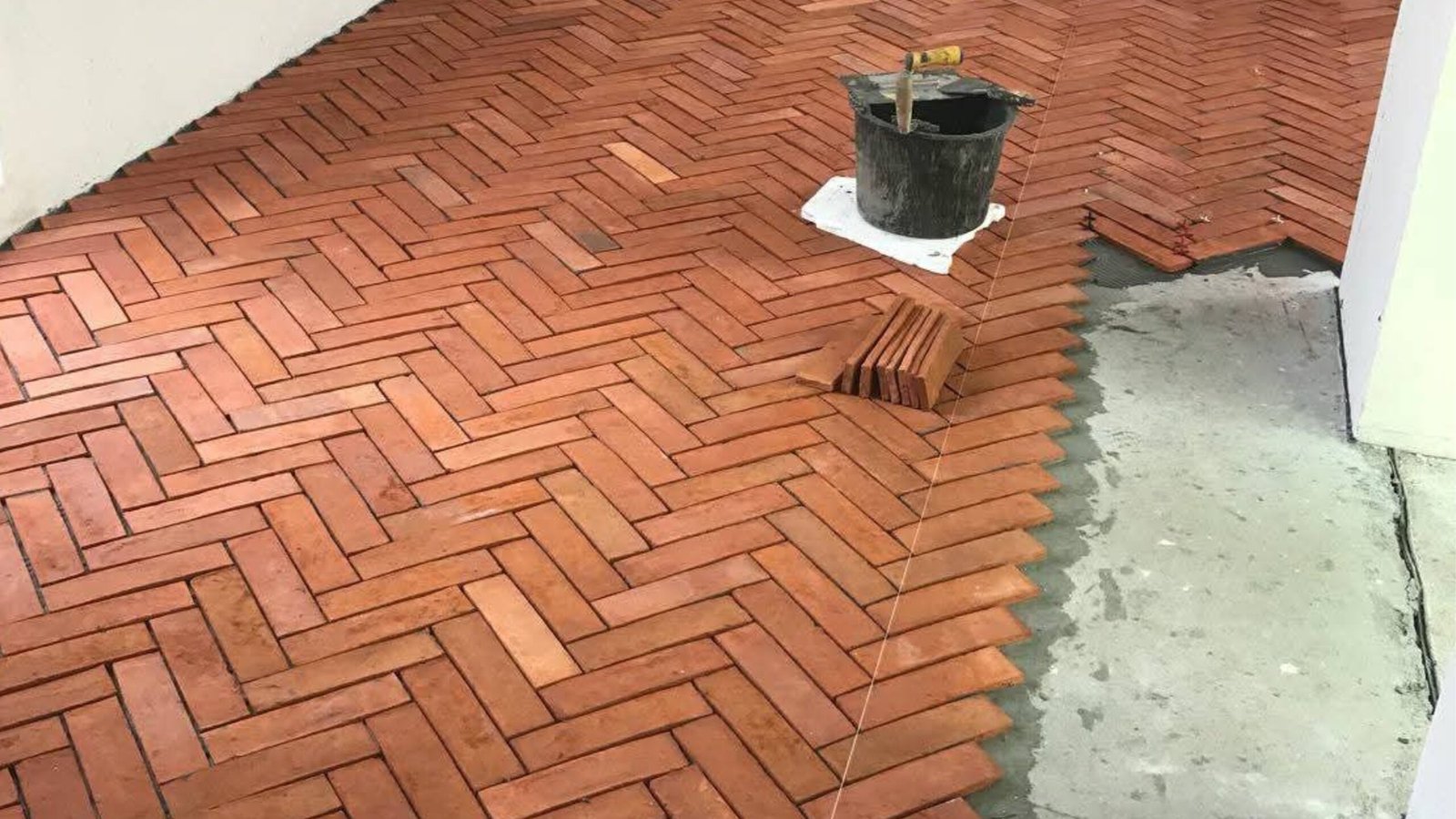 Verlegung von Terracotta Fliesen im Fischgrätmuster auf Estrich