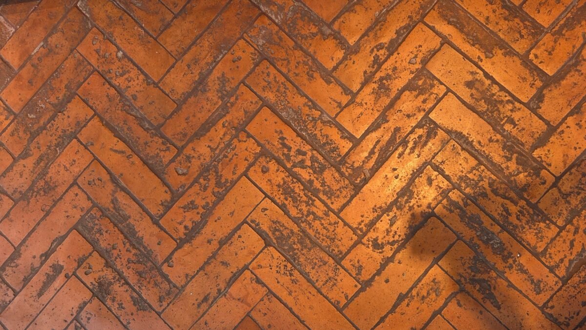 Detailaufnahme des Bodens mit handgefertigten Terracotta Fliesen im Fischgrätmuster.