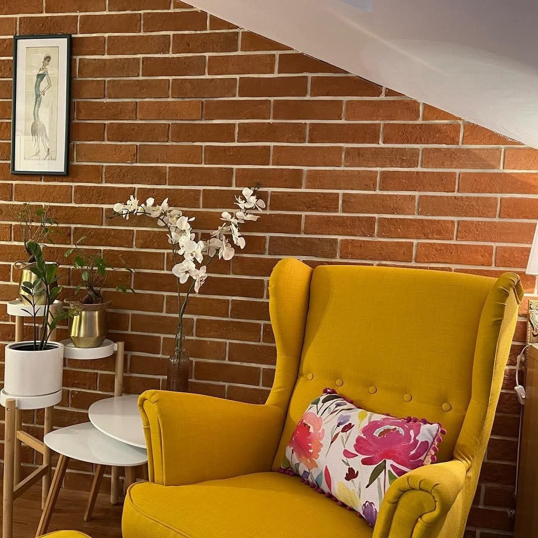 Homepage Wohnzimmer mit Terracotta Wandfliesen in Backsteinoptik und gelbem Sessel
